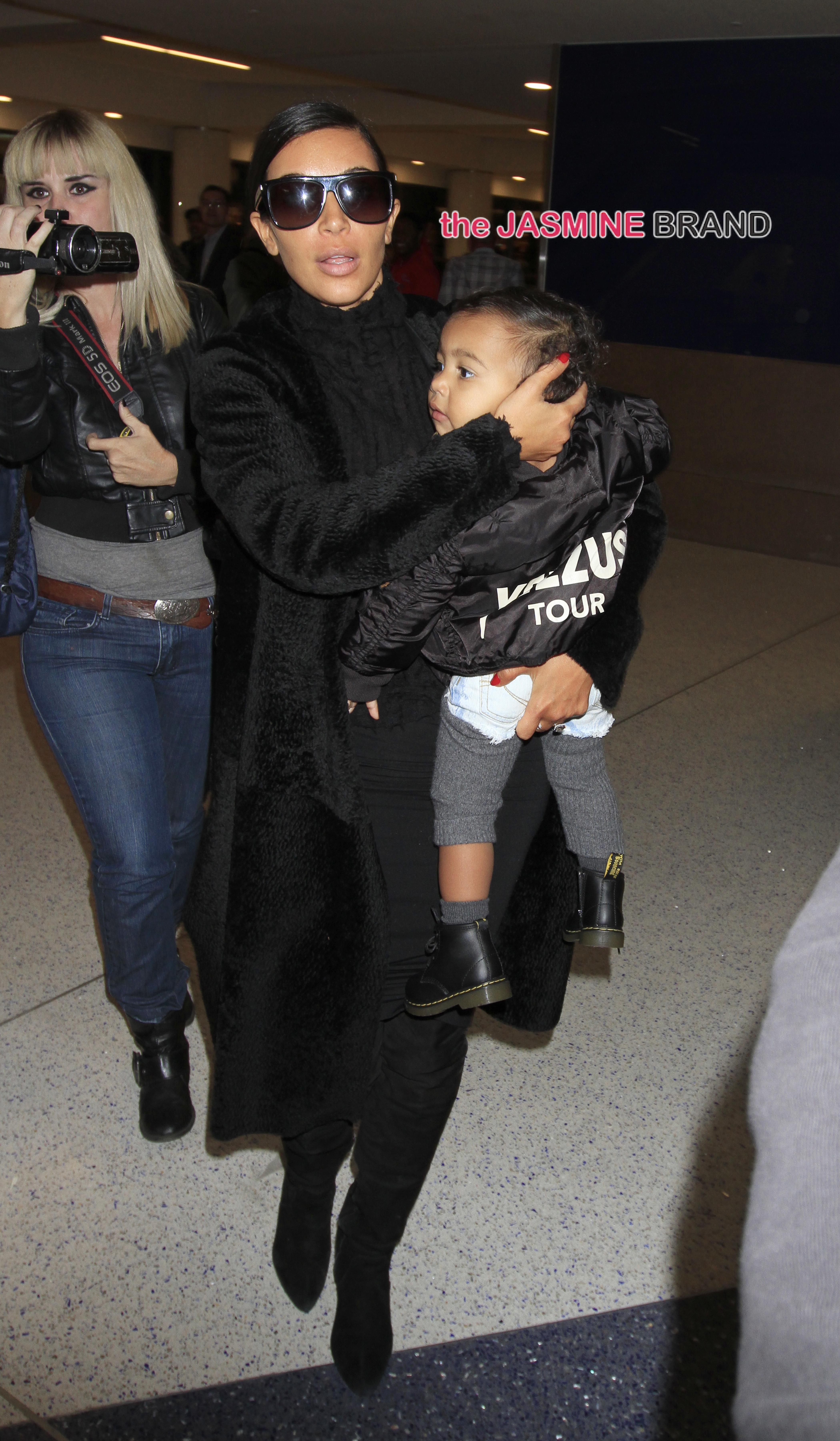 Kim Kardashian kisses baby North West as she carries her upon boarding a flight out of Los Angeles