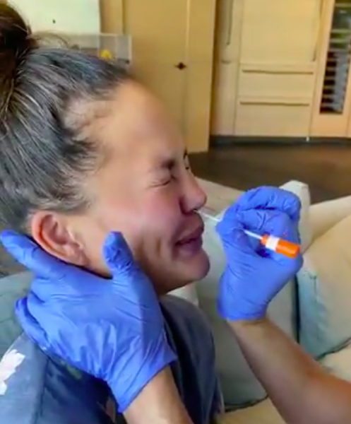 Chrissy Teigen Posts Graphic Video Of Getting Tested For COVID-19 + Reveals: I’m Getting My Boob Implants Out!